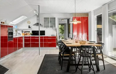 a kitchen with red cabinets and a wooden table with chairs at 3 Bedroom Awesome Home In Thyholm in Thyholm