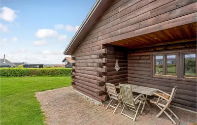 a table and chairs sitting outside of a cabin at Gorgeous Home In Vinderup With Sauna in Vinderup