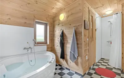a bathroom with a white tub and a wooden wall at Gorgeous Home In Vinderup With Sauna in Vinderup
