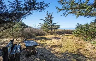 a wooden bench sitting on top of a hill next to the ocean at 3 Bedroom Gorgeous Home In Thyholm in Thyholm