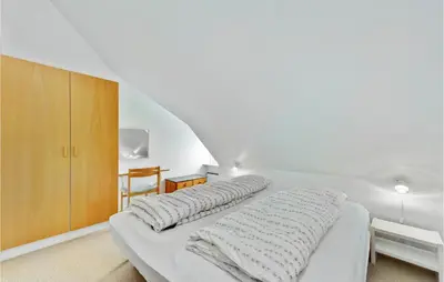 a white bedroom with a bed and a wooden cabinet at Gorgeous Apartment In Lemvig in Lemvig