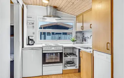 a kitchen with white appliances and wooden cabinets at Cozy Home In Hanstholm With Wifi in Hanstholm