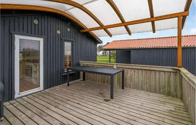 a wooden deck with a black table on it at Lovely Home In Hanstholm With Wifi in Hanstholm