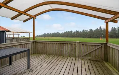 a wooden deck with a bench and a view of a field at Lovely Home In Hanstholm With Wifi in Hanstholm