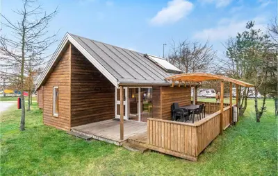 a wooden cabin with a deck with a table at 2 Bedroom Nice Home In Hanstholm in Hanstholm