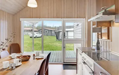 a kitchen with a dining table and a sliding glass door at 2 Bedroom Nice Home In Hanstholm in Hanstholm