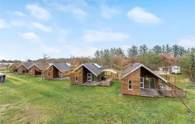 a row of log cabins on a grass field at 2 Bedroom Nice Home In Hanstholm in Hanstholm