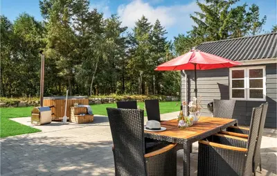 a patio with a table with a red umbrella at 4 Bedroom Amazing Home In Hurup Thy in Sønder Ydby