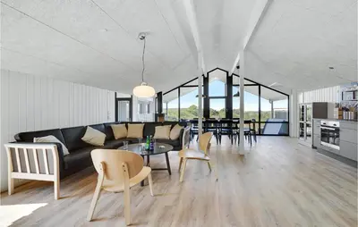 a living room with a couch and a table and chairs at Nice Home In Blokhus With Wifi in Blokhus