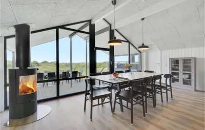 a dining room with a fireplace and a table and chairs at Nice Home In Blokhus With Wifi in Blokhus