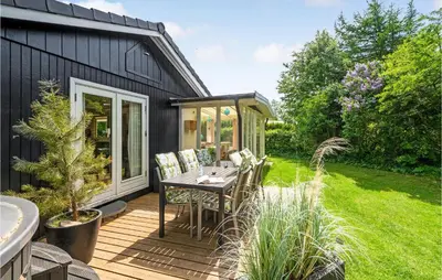 a backyard with a table and chairs on a deck at 2 Bedroom Awesome Home In Farsø in Farsø