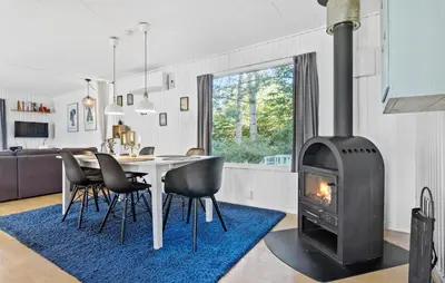 a living room with a fireplace and a table with chairs at 2 Bedroom Awesome Home In Farsø in Farsø