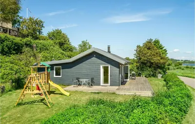a blue house with a slide and a playground at Cozy Home In Farsø With Sauna in Farsø