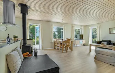 a living room with a fireplace and a dining room at Cozy Home In Farsø With Sauna in Farsø
