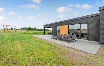 a black house with chairs and a playground at 4 Bedroom Awesome Home In Løgstrup in Løgstrup