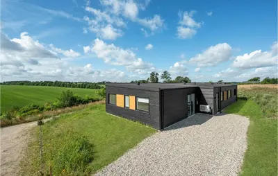 a black house on a hill with a gravel driveway at 4 Bedroom Stunning Home In Løgstrup in Løgstrup