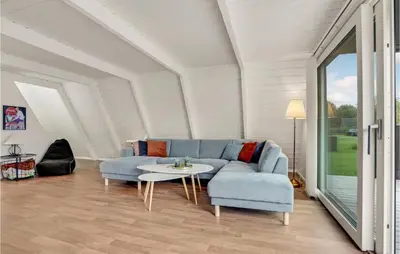 a living room with a blue couch and a table at 2 Bedroom Cozy Home In Farsø in Farsø