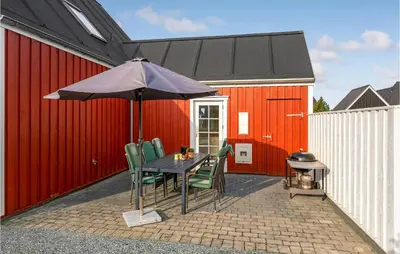 a table and chairs with an umbrella on a patio at Amazing Home In Blokhus With Wifi in Blokhus