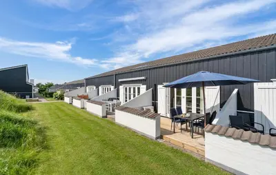 a building with a patio with a table and an umbrella at Agger Havn Feriecenter in Vestervig