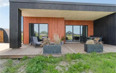 a house with a wooden deck with a chair at 3 Bedroom Amazing Home In Thisted in Thisted