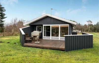 a black cabin with a deck in a field at Cozy Home In Pandrup With Kitchen in Pandrup