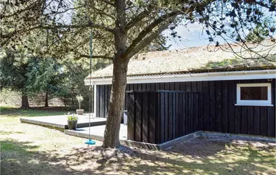 a black building with a tree next to it at 3 Bedroom Amazing Home In Pandrup in Pandrup