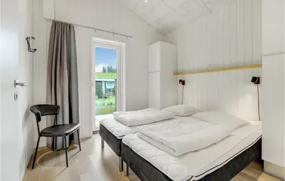 a bedroom with a bed and a chair and a window at Amazing Home In Blokhus With Sauna in Blokhus