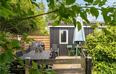 a tiny house with a deck with a table and chairs at Cozy Home In Roslev With Wifi in Roslev