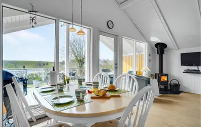 a dining room with a table with white chairs and a large window at Lovely Home In Roslev With Kitchen in Roslev