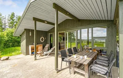 a patio with a wooden table and chairs on it at Lovely Home In Spøttrup in Spottrup