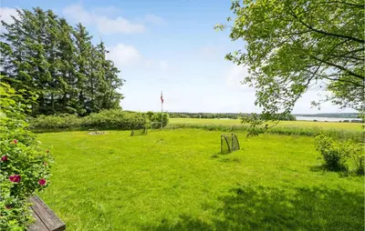 a field of grass with trees and a field of water at Lovely Home In Spøttrup in Spottrup