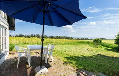 a table with chairs and an umbrella in a field at Cozy Home In Nykøbing M With Kitchen in Tæbring