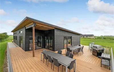 a black house with a deck with a grill at Lovely Home In Spøttrup With Wifi in Spottrup