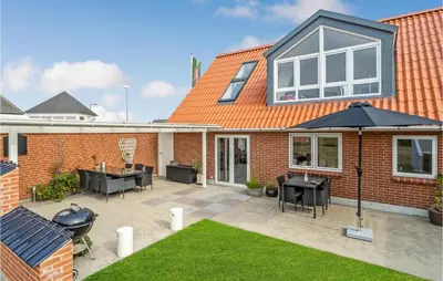 a brick house with an umbrella and a patio at Amazing Home In Vestervig With Sauna in Vestervig