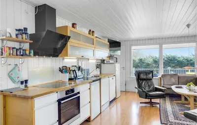 a kitchen with white cabinets and a table and a chair at 4 Bedroom Stunning Home In Thyholm in Thyholm