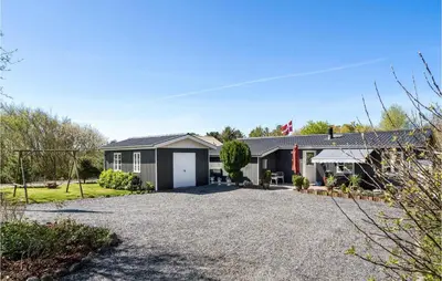 a house with a gravel driveway in front of it at 4 Bedroom Stunning Home In Thyholm in Thyholm
