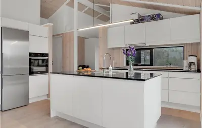 a kitchen with white cabinets and a black counter top at Cozy Home In Blokhus With Kitchen in Blokhus