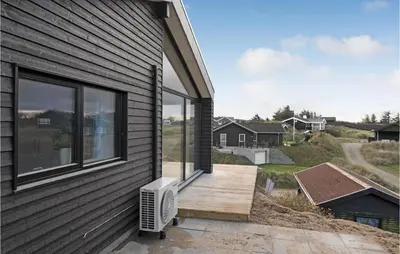 a house with a deck with an air conditioner on it at Cozy Home In Blokhus With Kitchen in Blokhus