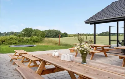 a wooden picnic table with flowers on a patio at Cozy Home In Spøttrup With Wifi in Spottrup