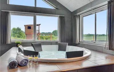 a large room with a tub with chairs and windows at Cozy Home In Spøttrup With Wifi in Spottrup