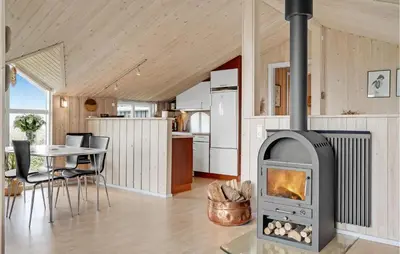 a fireplace in a living room with a table and a kitchen at Stunning Home In Lemvig With Wifi in Lemvig