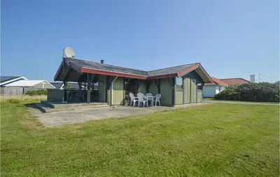 a green house with chairs and tables in a yard at 3 Bedroom Stunning Home In Blokhus in Blokhus