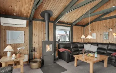 a living room with a leather couch and a fireplace at 3 Bedroom Stunning Home In Blokhus in Blokhus
