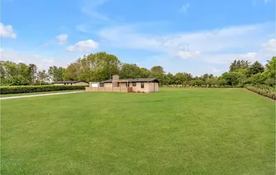 a large grass field with a building in the background at 3 Bedroom Lovely Home In Spøttrup in Spottrup