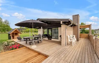 a wooden deck with a table and an umbrella at 3 Bedroom Lovely Home In Spøttrup in Spottrup