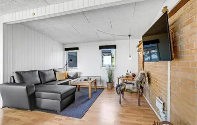 a living room with a couch and a tv at Cozy Home In Vesløs With House Sea View in Øsløs