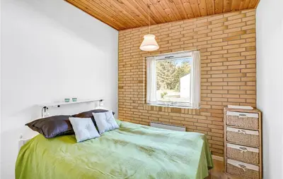 a bedroom with a bed and a brick wall at Cozy Home In Vesløs With House Sea View in Øsløs