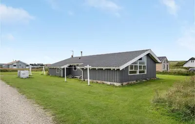 a house on a grass field next to a road at Cozy Home In Harboøre With Sauna in Harboør