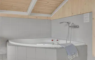 a bath tub in a bathroom with two wine glasses at Cozy Home In Harboøre With Sauna in Harboør