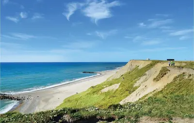 a beach with people standing on top of a cliff at Cozy Home In Harboøre With Sauna in Harboør